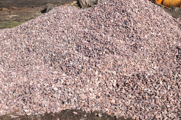 Crushed stone mound. Red crushed stones. Versatile building material for horticulture, landscape gardening or road construction. Material for railroad construction. - obrazy, fototapety, plakaty