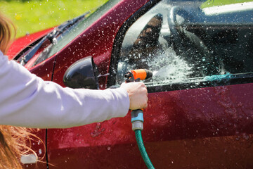 Woman washing car outdoor. Hand holding water hose pistol. Car detailing background. Water stream pressure. No chemicals car wash.