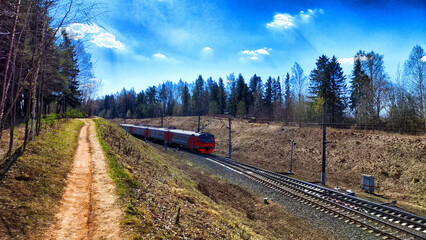 A railway with rails in autumn or spring on a sunny day. Landscape with trees and a slope