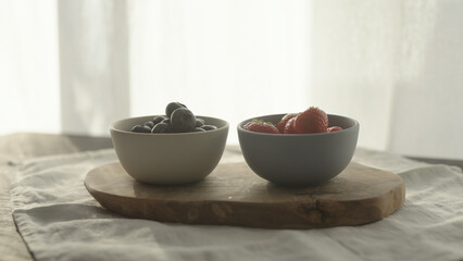 fresh blueberries and strawberries in ceramic bowls with natural light