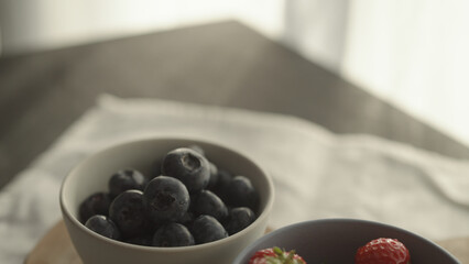 fresh blueberries and strawberries in ceramic bowls with natural light