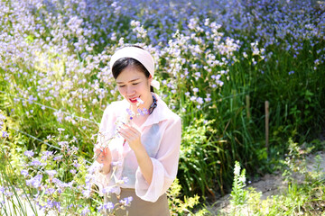 Beautiful Asian woman is smiling and relaxing in blooming purple Murdannia giganteum flowers field
