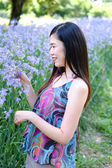 Beautiful Asian woman is smiling and relaxing in blooming purple Murdannia giganteum flowers field
