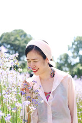 Beautiful Asian woman is smiling and relaxing in blooming purple Murdannia giganteum flowers field
