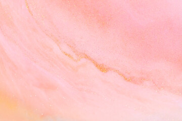 White and pink acrylic paints with shimmering golden glitter. Liquid paint abstract background.