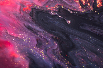 Colorful liquid paint abstract background. Pink, purple and black acrylic paints with golden...
