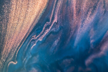 Colorful liquid paint abstract background. Blue and purple acrylic paints with golden glitter 