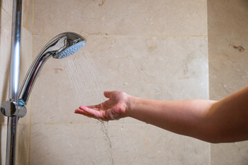 Water flows from the shower head as person showers in bathroom