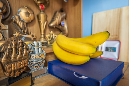 Fresh ripe banana fruit on bedroom shelf with sport award on background