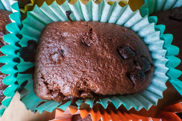 Homemade baked chocolate cupcake with chocolate chips sitting inside colorful baking liner inside...