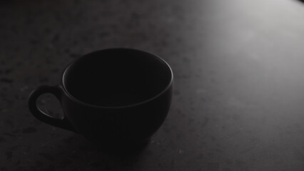 black cup on concrete countertop with copy space under dim light