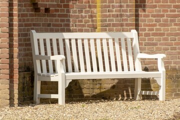white wooden bench with brick wall