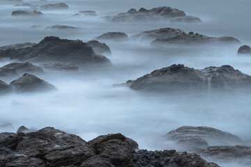 Long exposure of coastline with tide and rocks, like clouds flowing between it, in Keelung city, Taiwan.