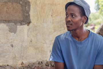 Fototapeta premium village african man in the yard, profile view, casual clothing with blue shirt