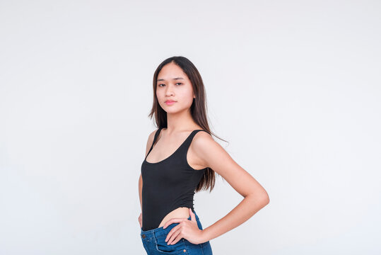 Front view of a young asian woman in a black bodysuit and shorts, hands on hips. Isolated on a white background.