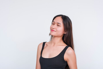 Obraz premium An image of a serene young Asian woman wearing a black bodysuit, isolated on a white backdrop, exuding a sense of bliss.
