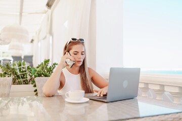 Woman coffee cafe macbook. Woman sitting at a coffee shop with mobile phone drinking coffee and looking away. Caucasian female relaxing at a cafe.