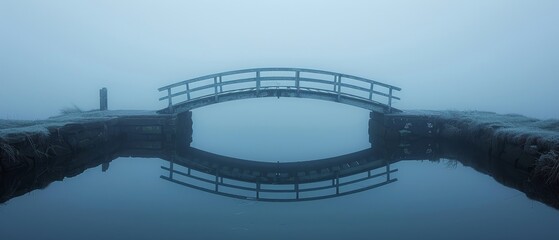 Silhouetted bridge over river on a foggy morning evokes a serene, solitary atmosphere