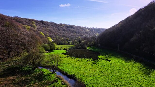 Aerial drone shot flying low along a tree lined valley in Wales
