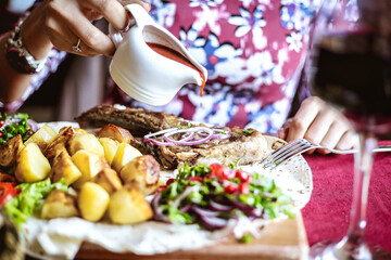 Woman Pouring Sauce Over a Plate of Food