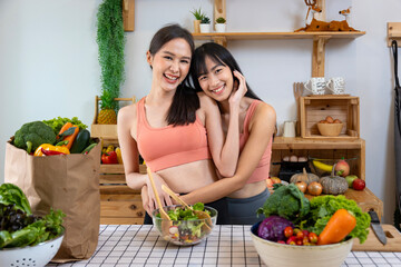 Asian couple of same sex marriage hugging each other while cooking healthy salad together in...