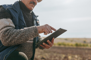 Wisdom in Touch Farmer Senior Examining Soil Conditions on Tablet