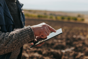 Analyzing Earth Bounty Senior Farmer hands Examining Soil with Tablet