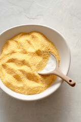 Maize flour in a bowl on delicate background.