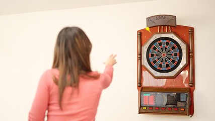 Rear view of a woman playing darts at home