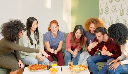 Multiracial group of happy friends eating pizza at home