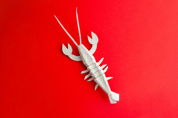 Close-up paper lobster on red surface. Folk art, highly detailed product photo.