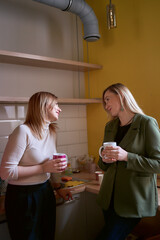 two women talking over coffee in the office kitchen