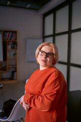 Fototapeta premium portrait of a woman with a disability in an orange sweater and leather pants in the office