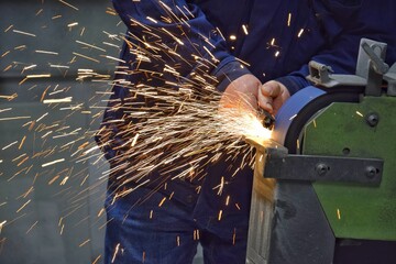 Hand sharpening on a grinding machine with sparks close up - obrazy, fototapety, plakaty