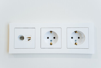 Three white wall sockets symmetrically placed on a white wall plate