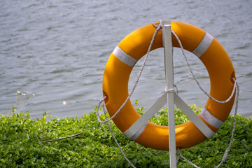 Yellow lifebuoy is on the edge of the lake for safety.