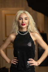 Portrait of a young beautiful blonde girl in a black dress in the studio.