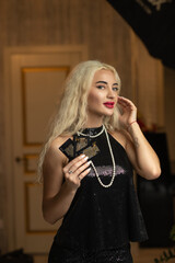 Portrait of a young beautiful blonde girl in a black dress in the studio.