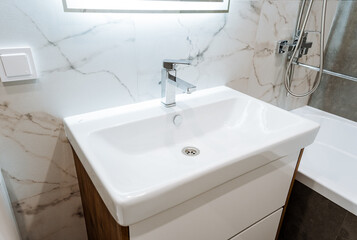 A rectangular bathroom with a sink, shower, tap, and plumbing fixtures