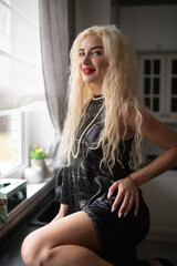 Portrait of a young beautiful blonde girl in a black dress in the studio.