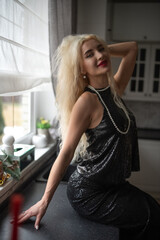 Portrait of a young beautiful blonde girl in a black dress in the studio.