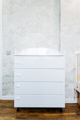 Wood chest of drawers on wheels by crib in nursery