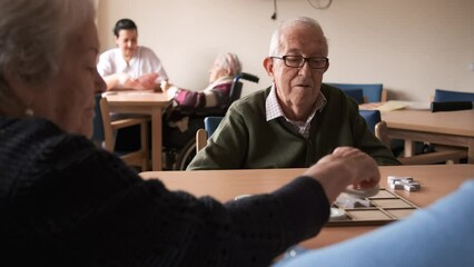 Elderly people chatting with young woman while playing board game