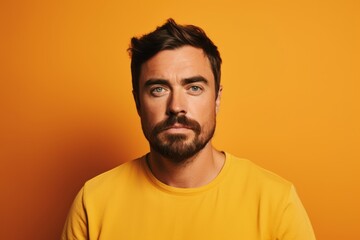 Obraz premium Portrait of a pensive man looking at camera over yellow background