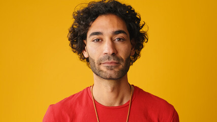 Close up, attractive man with curly hair, dressed in red T-shirt,  looking at camera isolated on...