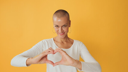 Young hairless woman showing representing heart in shape of fingers gesture at camera isolated on...