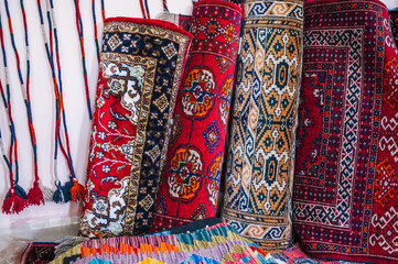 stack of rolled up traditional oriental uzbek handmade carpets at the market in Uzbekistan in...