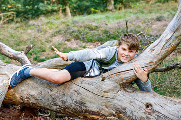 Teenager boy hiking in the forest on summer day. School child having fun with active leisure for family