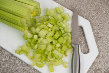 Diced green celery stalks on stone white board top view.
