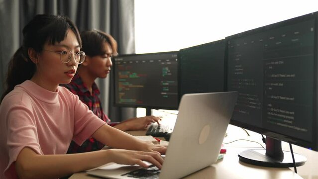 Slow motion back end software developer engineer for computer programming working together on debugging writing computing code, solving complex algorithms display on monitor in office. Burgeoning